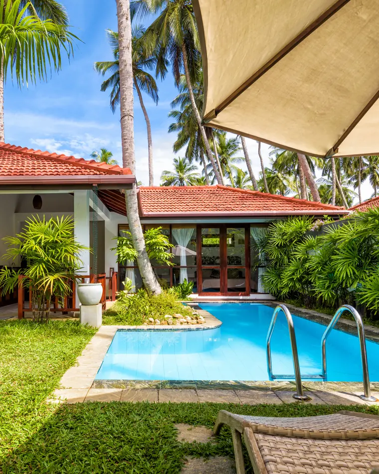Illustrative photo: single-storey villa with a pool and tropical garden, location not specified